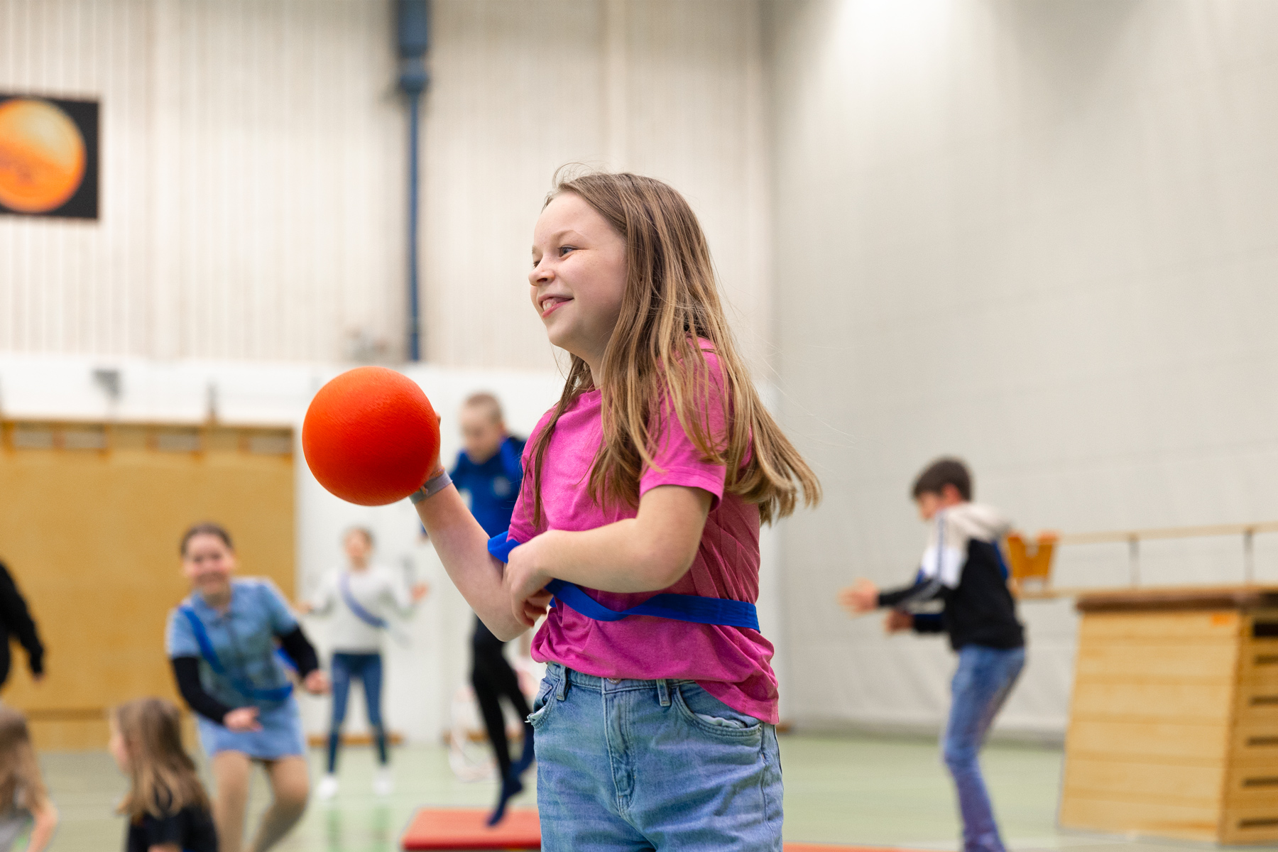 Tjej som spelar boll i gymnastiksal
